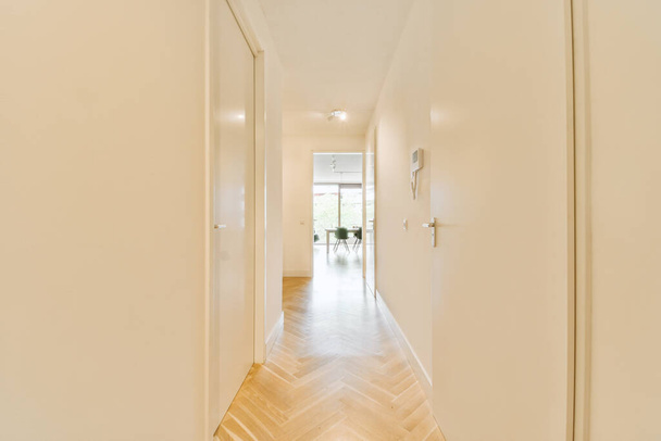 Wnętrze nowoczesnego mieszkania w minimalnym stylu z wąskim pustym korytarzem oświetlonym lampami - Zdjęcie, obraz