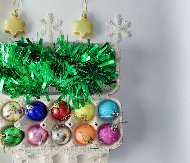 Świąteczne dekoracje. Zielony deszcz, świąteczne kulki i gwiazdy. Pudełka z jajkami. Świąteczne dodatki. Miejsce do podpisu. Nastrój noworoczny - Zdjęcie, obraz