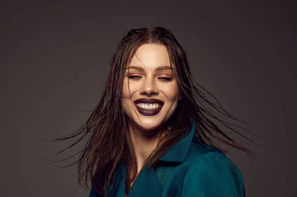 Happiness. Excited young beautiful girl with artistic makeup and purple lipstick on her lips laughing isolated over grey background. Style, beauty, high fashion, magazine style and ad - Photo, image