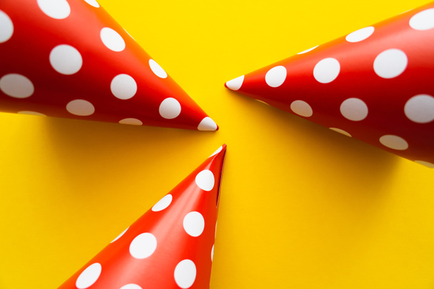 Top view of dotted party caps on yellow background  - Фото, изображение