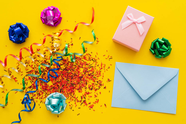 Top view of envelope near gift and sweet sprinkles on yellow background  - Fotografie, Obrázek