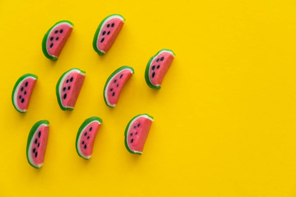 Top view of sweet candies in watermelon shape on yellow background  - Foto, Imagen