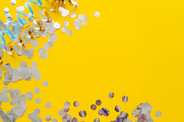 Vue du dessus de serpentine colorée et confettis sur fond jaune  - Photo, image