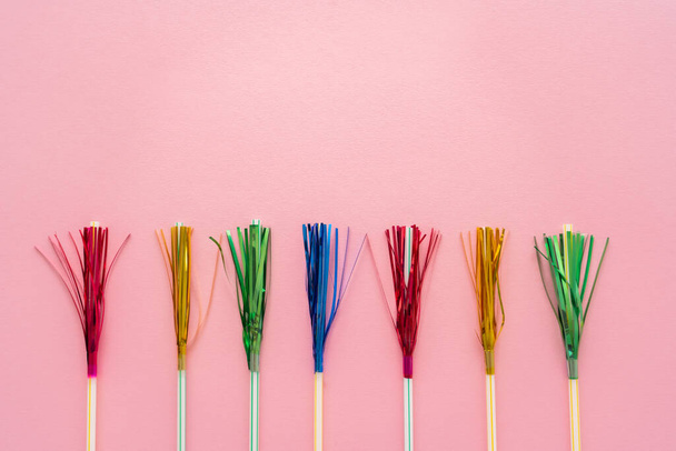 Top view of drinking straws with colorful tinsel on pink background with copy space - Zdjęcie, obraz
