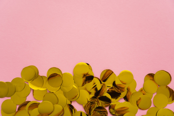 Top view of golden confetti on pink background with copy space  - Foto, afbeelding