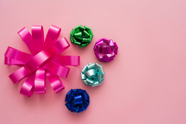 Top view of different colorful gift bows on pink background  - Фото, зображення