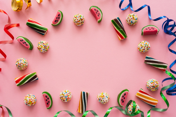 Puesta plana con caramelos de colores y serpentina sobre fondo rosa  - Foto, imagen