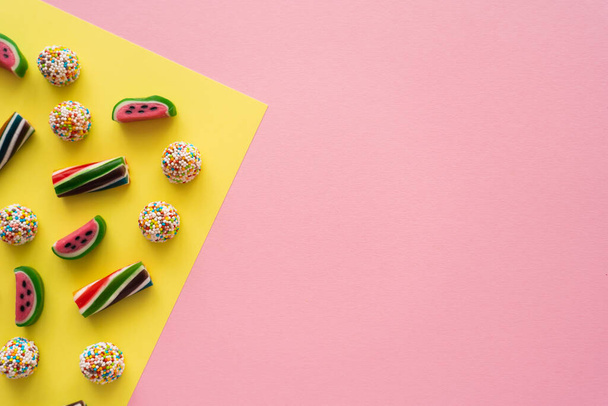 Bovenaanzicht van lekkere snoepjes op gele en roze achtergrond  - Foto, afbeelding