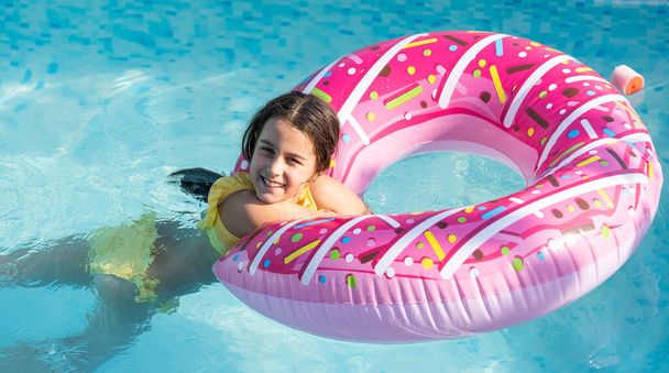 Bella bambina nuotare nella piscina all'aperto e divertirsi con cerchio gonfiabile. - Foto, immagini