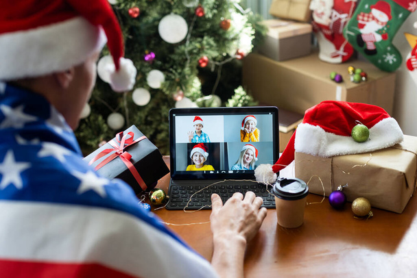 homme célèbrent le Nouvel An, assis, bavarder et sourire près de la tablette dans chapeaux Santas - Photo, image