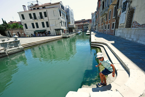 Boy in panama and sunglasses stand near canal in Venice, Italy. - Foto, Bild
