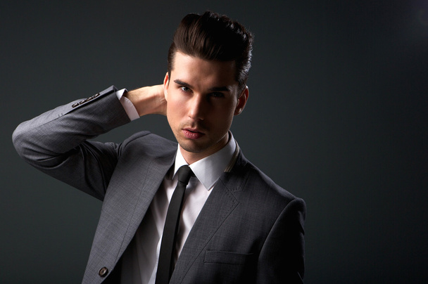 stylischer junger Mann im Business-Anzug mit der Hand im Haar - Foto, Bild