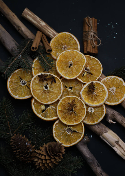 dried oranges cones cinnamon fir branches and star anise beautifully laid out on wooden natural sticks christmas decoration on a dark background. for cards calendar labels signage invitation banners flyers - Fotó, kép