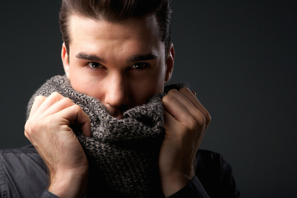 Cool guy holding grey wool scarf over face - Photo, Image