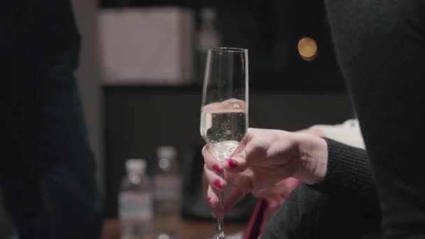 Chica vestida de negro en una celebración con una copa de champán en la mano - Metraje, vídeo