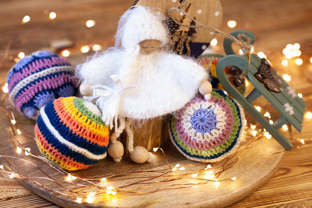 játék horgolt karácsonyi angyal karácsonyfa dekoráció körül színes golyók és karácsonyi led fények - Fotó, kép