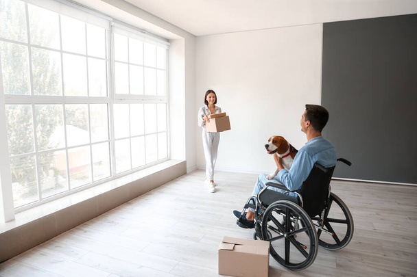 Jovem mulher e seu marido em cadeira de rodas com cão em seu novo apartamento no dia em movimento - Foto, Imagem