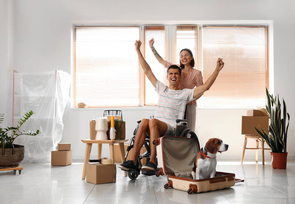 Nuori nainen miehensä kanssa pyörätuolissa ja koira uudessa talossaan muuttopäivänä - Valokuva, kuva