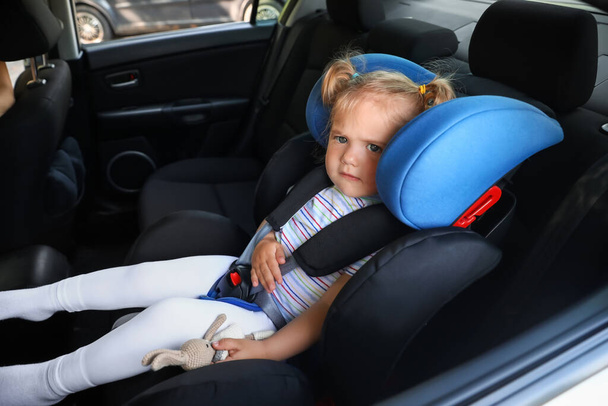 Adorable petite fille bouclée dans le siège de sécurité de voiture - Photo, image