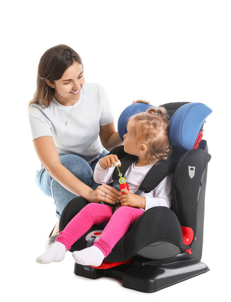 Madre y su pequeña hija se abrocharon en el asiento de seguridad del coche sobre fondo blanco - Foto, Imagen