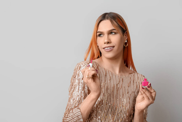 Mladá transgender žena s růžovým lak na nehty na světlém pozadí - Fotografie, Obrázek