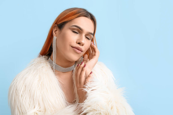 Young transgender woman with beautiful manicure on blue background - Foto, Imagen