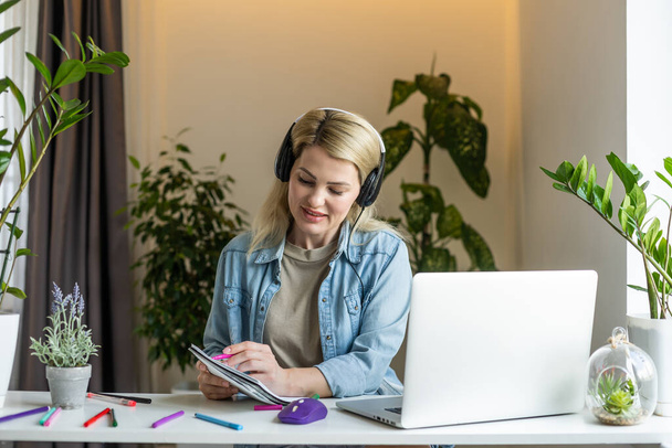Spotkanie online. Młoda kobieta nosząca słuchawki za pomocą laptopa oglądająca webinar lub robiąca wideo czat przez kamerę internetową. Konferencja biznesowa. Koncepcja e-kształcenia. - Zdjęcie, obraz
