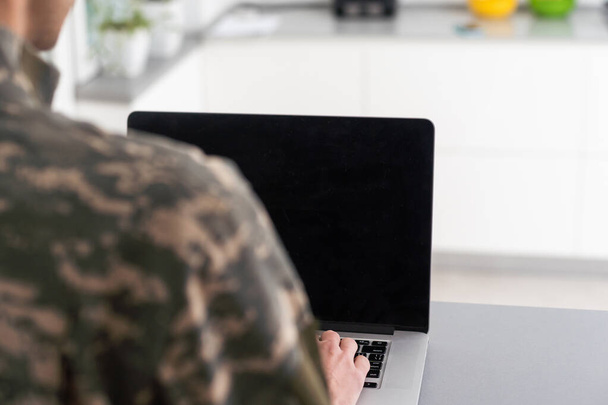 Surveillance and control of opposing information concept, Soldier in camouflage uniform working on laptop for Information Operation. - Photo, image