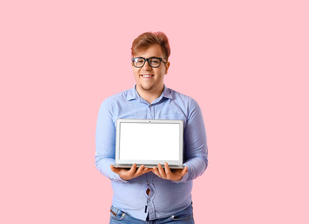 Jovem homem com sobrepeso com laptop no fundo rosa - Foto, Imagem