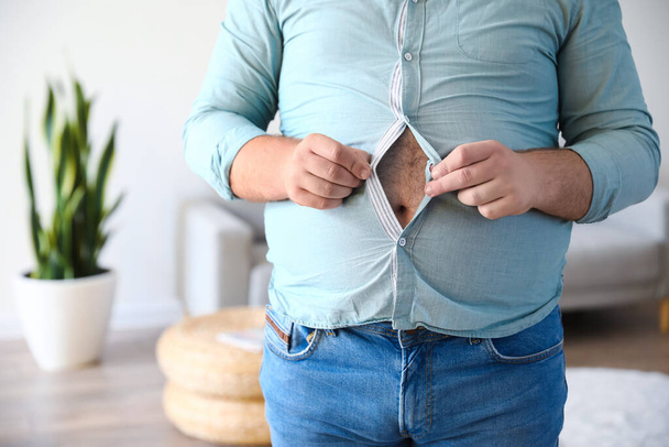 Mladý muž s nadváhou v těsné košili doma, detailní záběr - Fotografie, Obrázek