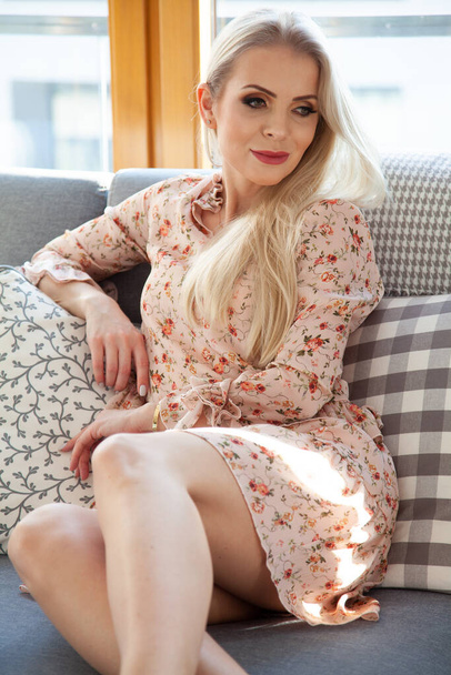 Portrét atraktivní mladé blondýny hezká žena v květinových šatech sedí na kočáru - Fotografie, Obrázek