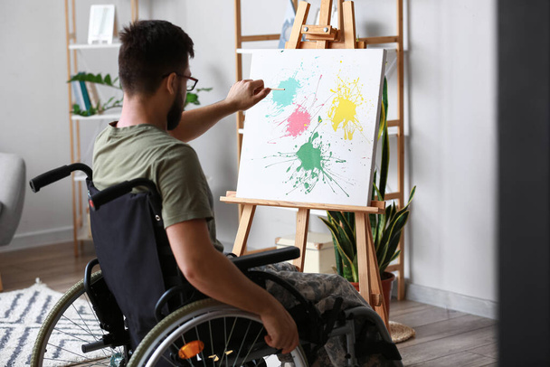 Joven soldado en silla de ruedas pintando en casa - Foto, imagen