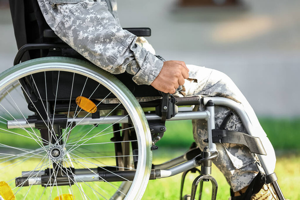 Young soldier in wheelchair outdoors, closeup - Foto, imagen