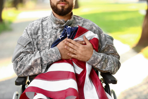 Νεαρός στρατιώτης σε αναπηρική καρέκλα με σημαία των ΗΠΑ σε εξωτερικούς χώρους, closeup - Φωτογραφία, εικόνα