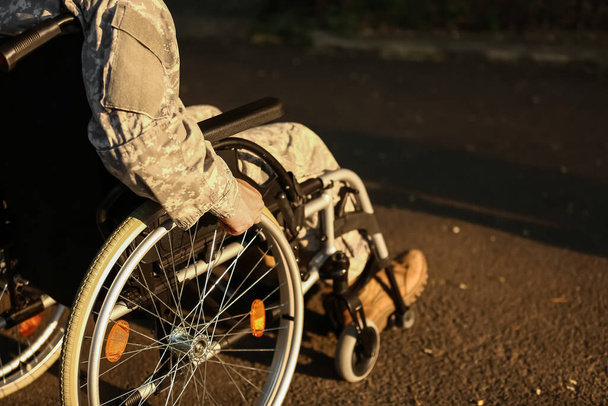 Young soldier in wheelchair outdoors, closeup - Foto, imagen
