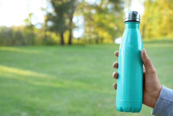 Man with sports water bottle in autumn park, closeup - Photo, Image