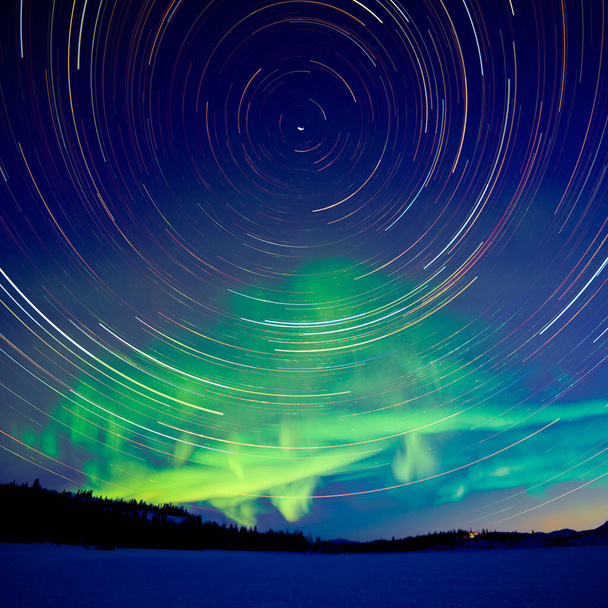 Senderos de estrellas de astrofotografía al amanecer con la exhibición verde brillante de auroras boreales o auroras boreales en el Territorio de Yukón, Canadá - Foto, imagen