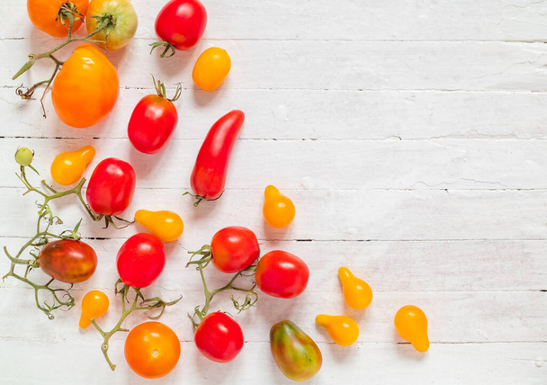 Tuoreet orgaaniset punaiset ja keltaiset tomaatit valkoisella puupohjalla. Kopioi tilaa. Yläkuva. - Valokuva, kuva