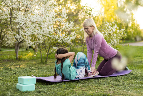 Mother and her daughter outdoors doing yoga, healthy lifestyle - Photo, Image