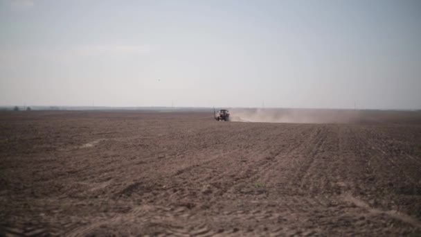 畑の播種トウモロコシのプランター付きトラクター。農業と農業を産業規模で。遠くのトラクターは、地球のほこりを拾う - 映像、動画