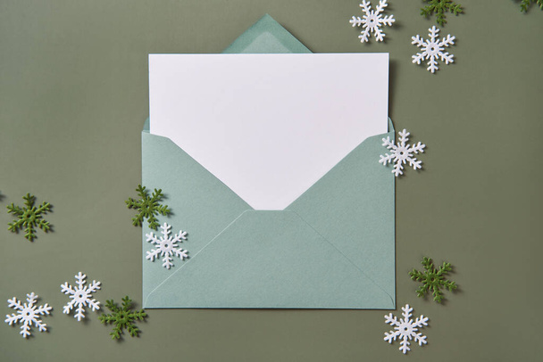 Різдвяна листівка лежала. Порожня картка в зеленому конверті. Свято та макет запрошень
. - Фото, зображення