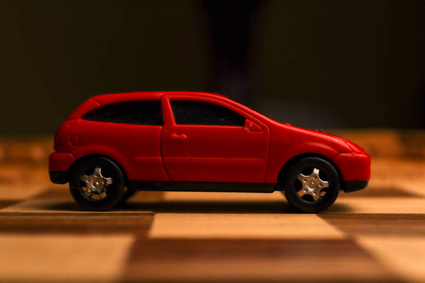 Giocattolo veicolo rosso su una scacchiera con vari modelli unici disegnati su di esso - Foto, immagini