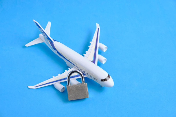 Passenger plane and lock on blue background.Concept of ban passenger flights - 写真・画像