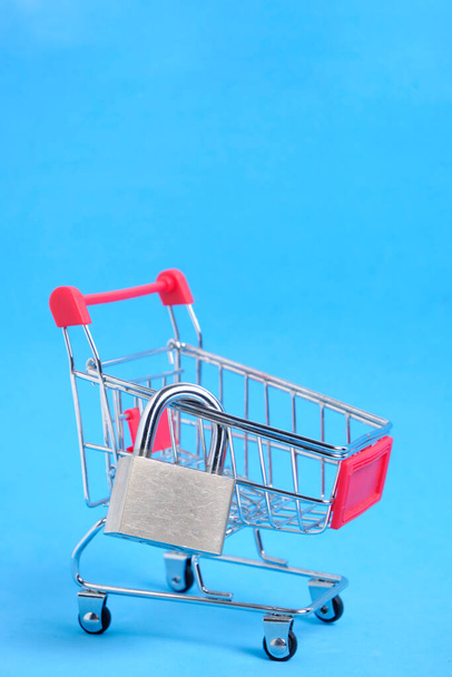 Shopping cart and padlock closed on it, business concept, budget reduction and minimalistic shopping - Fotoğraf, Görsel