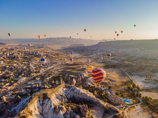 Colorful hot air balloons flying over at fairy chimneys valley in Nevsehir, Goreme, Cappadocia Turkey. Spectacular panoramic drone view of the underground city and ballooning tourism. High quality. - Photo, image
