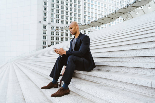 young business man sitting and working in the financial street area of the city .Representation of a successful sales person reaching the top of the career. - 写真・画像