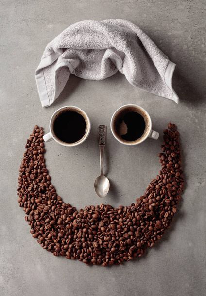 Koffie concept op een grijze stenen achtergrond. Koffiekopjes, handdoek en lepel. De compositie is als een menselijk gezicht. - Foto, afbeelding