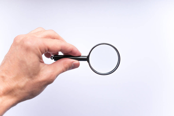 Magnifying glass in hand on white background, isolated, copy space for your image or text. Concept of search. - 写真・画像