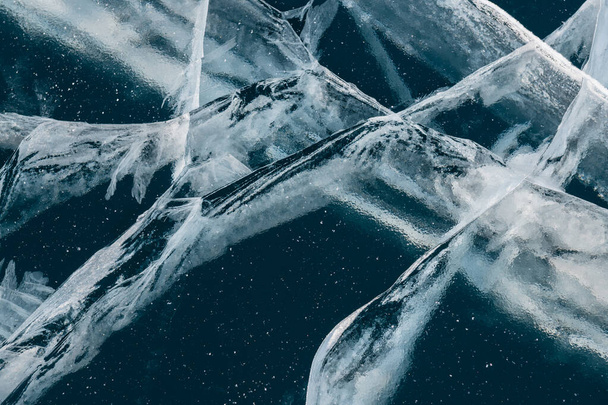 Transparent blue ice with cracks on the lake in winter. Abstract winter nature background. Baikal, Russia - Photo, image