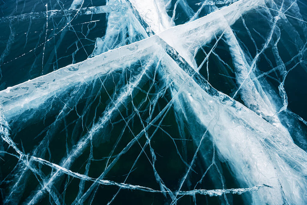 Transparent blue ice with cracks on the lake in winter. Baikal, Russia. Abstract winter nature background - Zdjęcie, obraz